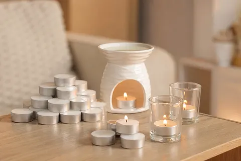 Bougies chauffe-plat blanches empilées et allumées dans des photophores près d'un brûle-parfum en céramique