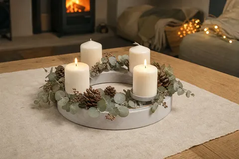 Couronne de l'Avent ronde en bois blanc-gris avec quatre bougies blanches sur une table en chêne