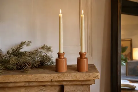Deux chandelles rustiques ivoire de 27 cm dans des bougeoirs en céramique sur une cheminée