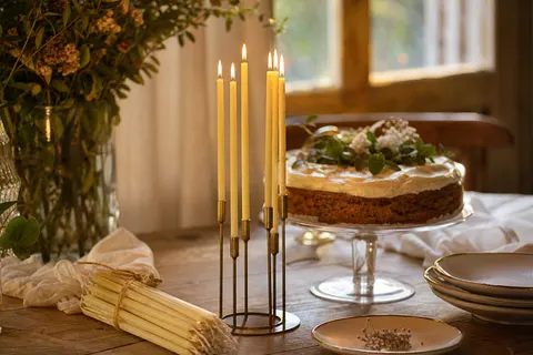 Fines chandelles ivoire en cire d'abeille allumées dans un chandelier en laiton sur une table de fête