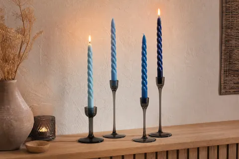 Quatre bougies torsadées bleues de 25 cm dans des bougeoirs en verre sur une console en bois